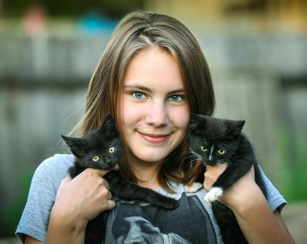 Young lady holding 2 kittens